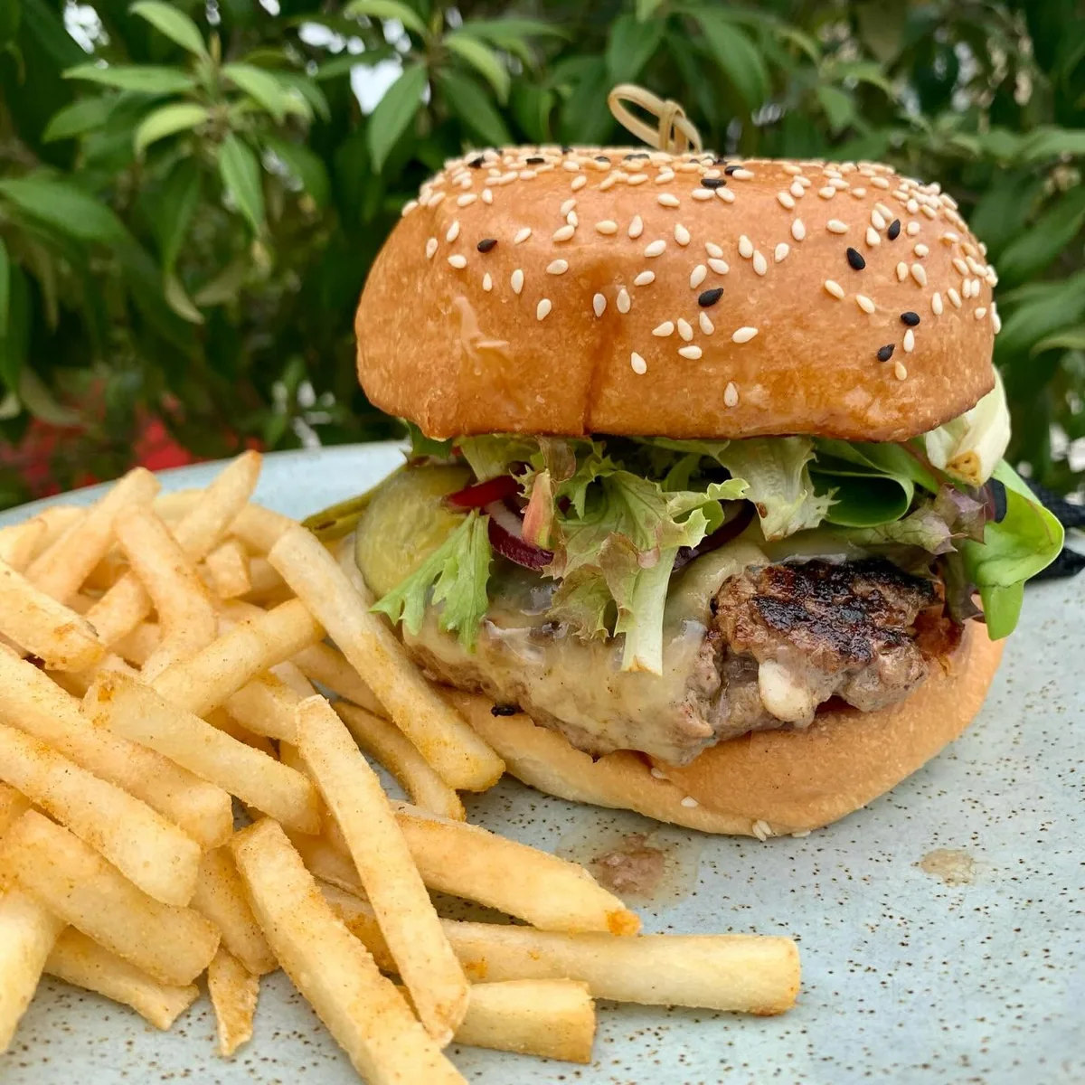 A burger and golden fries beside the greenery at Elderflower Café