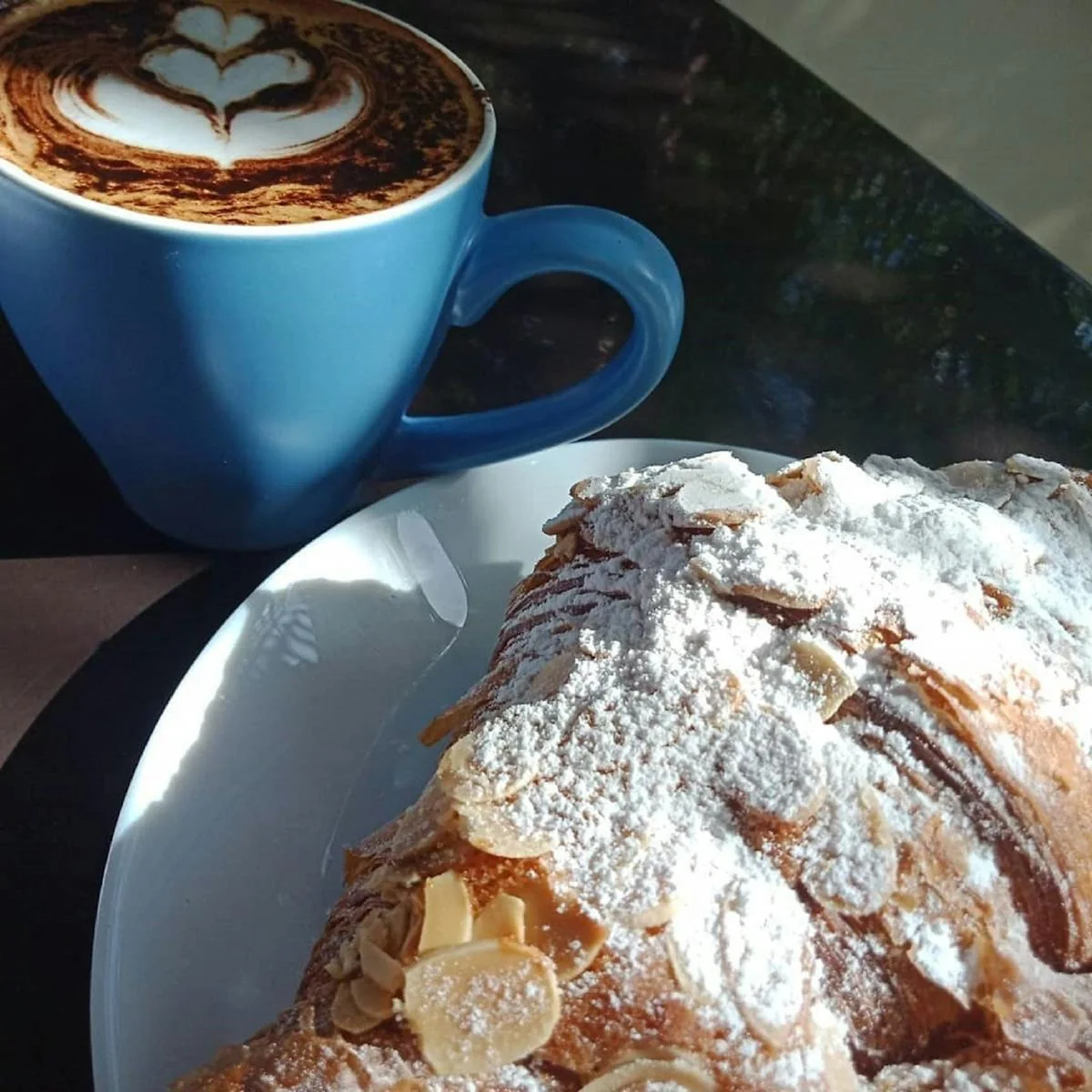 An almond croissant and a blue cup of coffee in the café